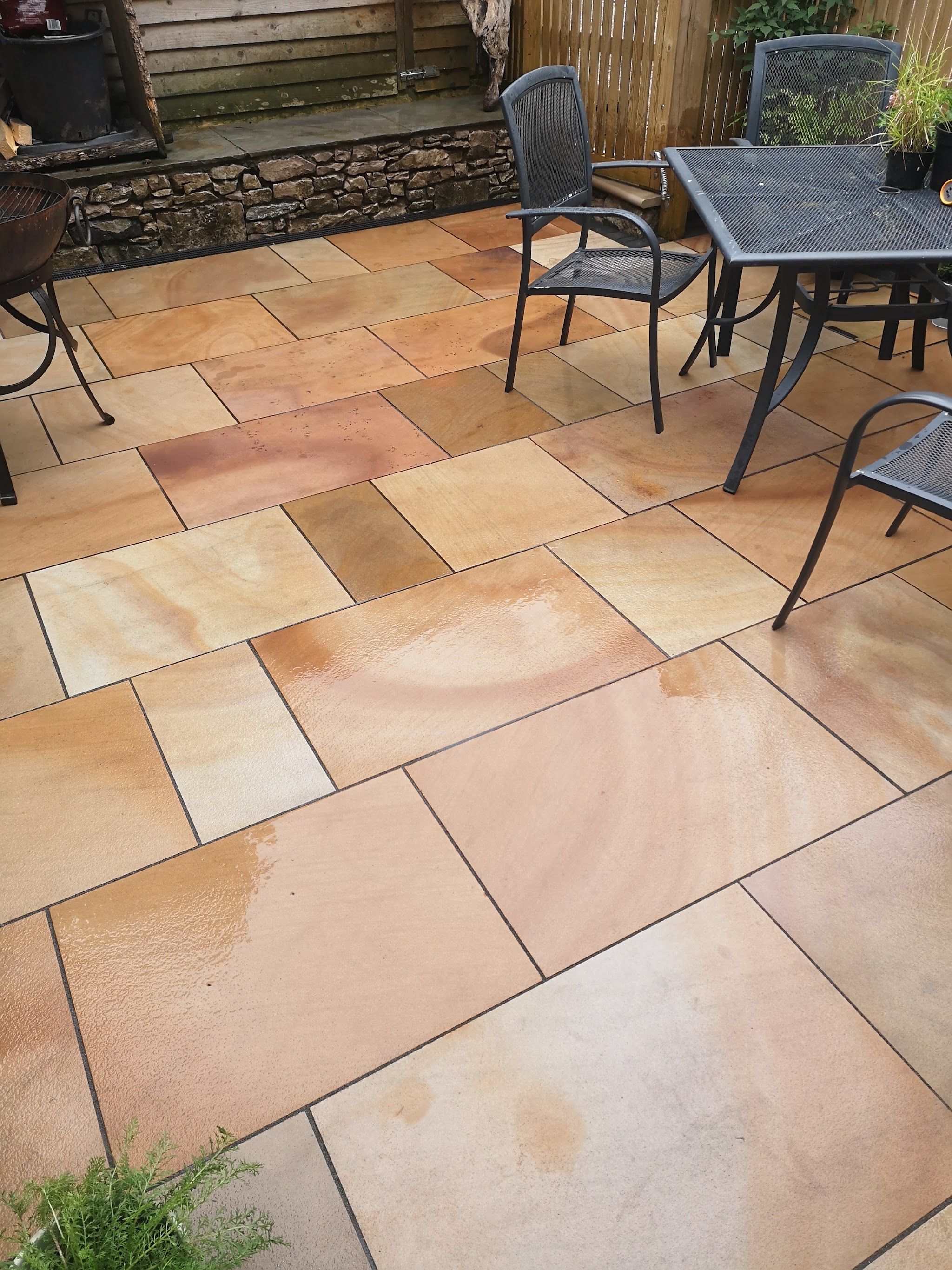 Sandstone patio with garden furniture and a stone wall behind