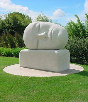 A carved stone head sculpture on a lawn