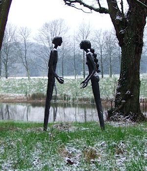 Two tall figure sculptures by the lake in snow