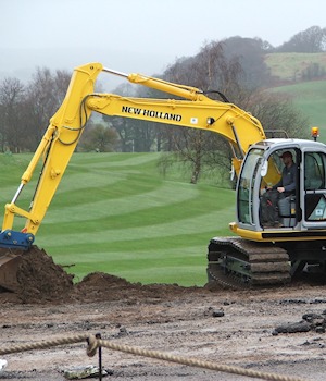 An excavator at work beside the golf course